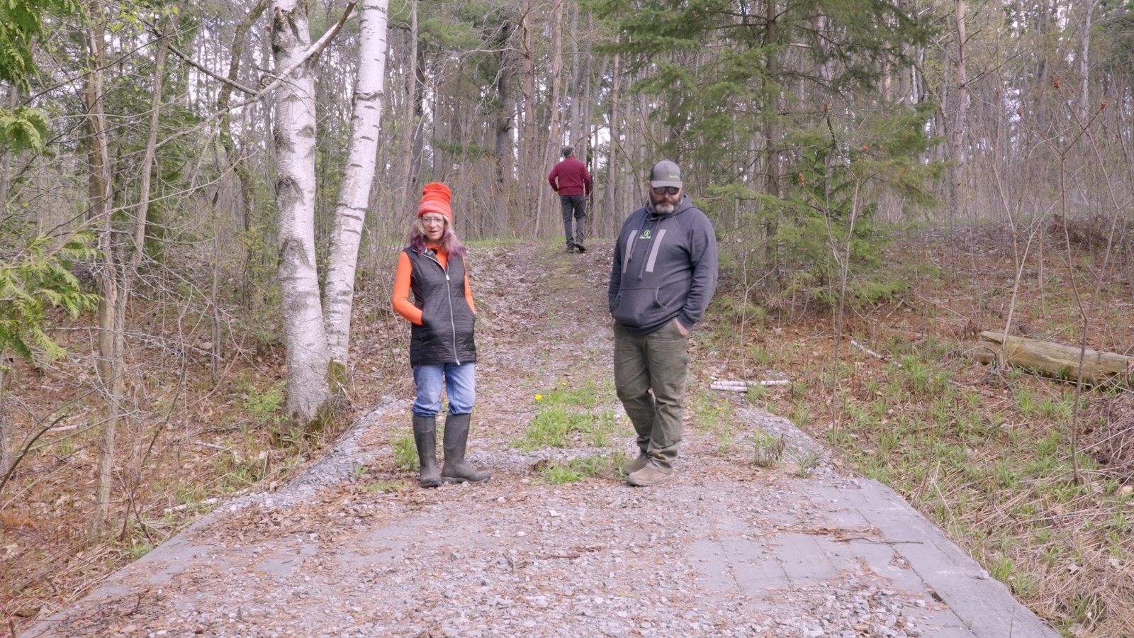 Two people walking a wide finished forest trail beside a timber crossing